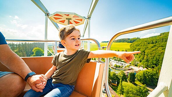 Im Riesenrad Big Wheel macht der kleine Junge große Augen und bewundert die beeindruckende Landschaft.