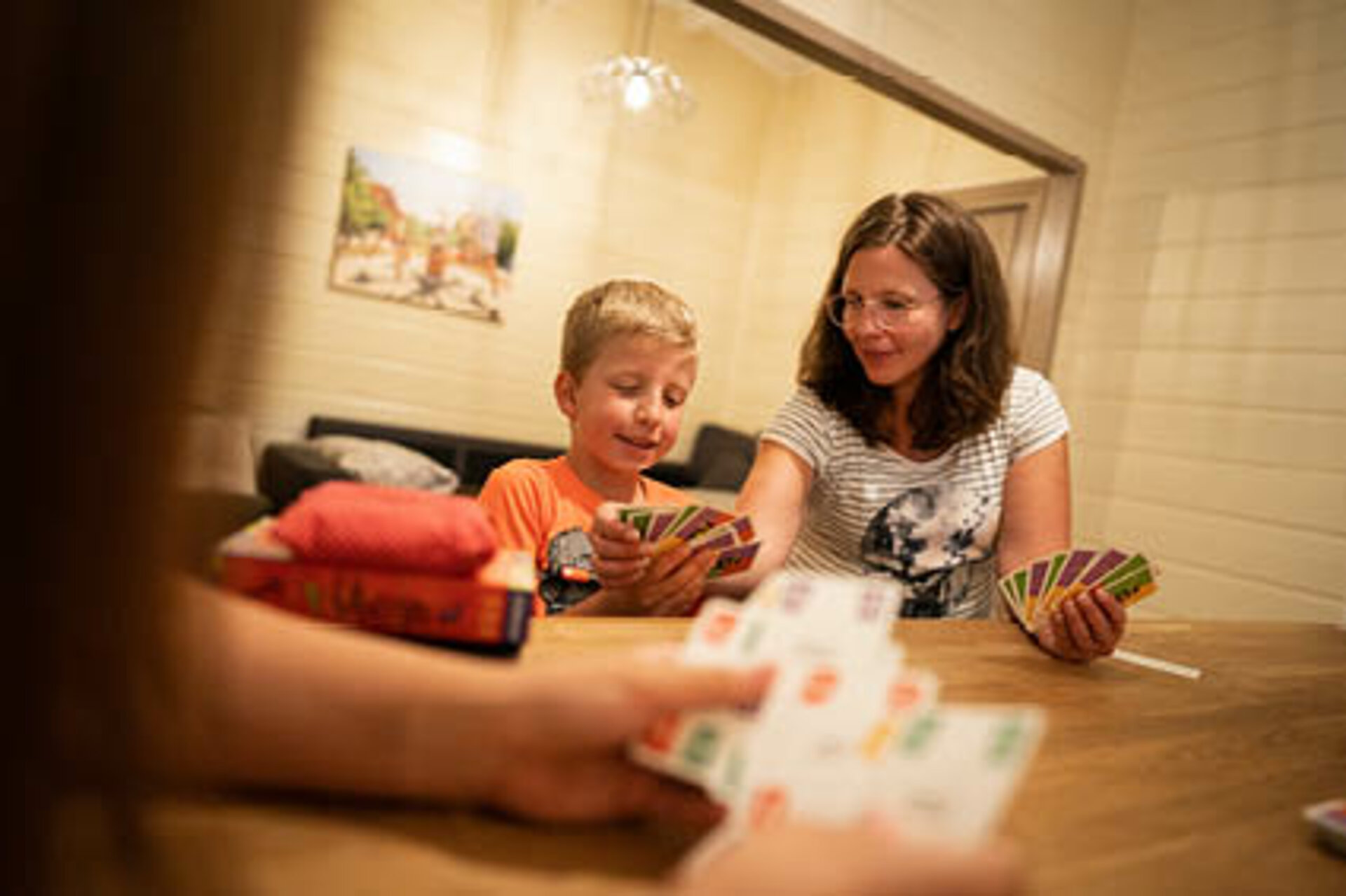 Die Mama erklärt dem Sohn die Regeln beim Kartenspielen.