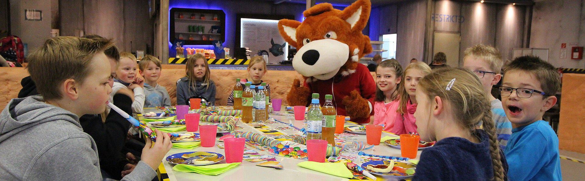 Am bunt gedeckten Tisch feiert das Geburtstagskind ausgelassen mit seinen Gästen einen tollen Kindergeburtstag.