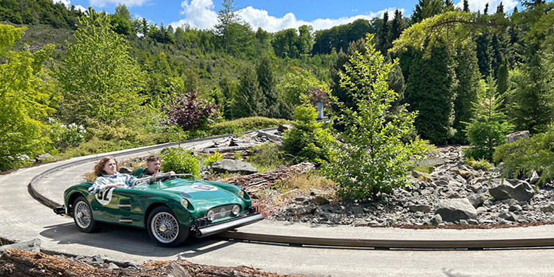 Zwei Jungs geben in einem grünen Oldtimer kräftig Gas bei der Rocky Mountain Rallye.