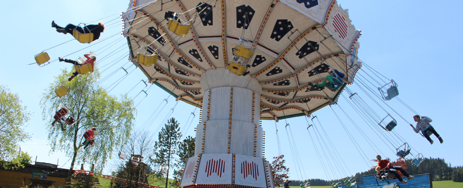 Bei schönem Wetter erstrahlt der Wellenflieger, das Kettenkarussell, im Freizeitpark im vollen Glanz.