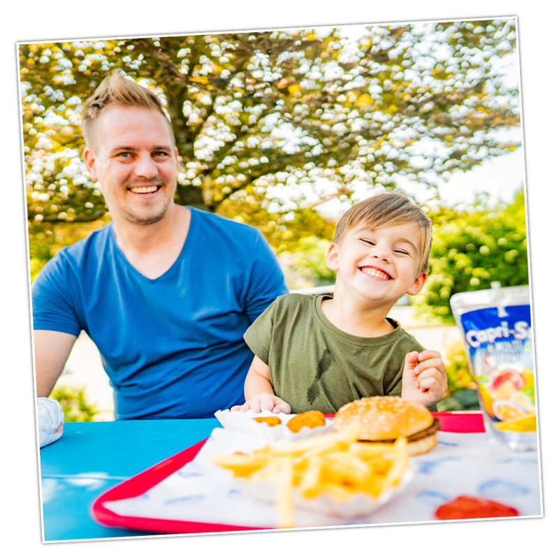 Der Papa hat mit seinem Sohn richtig Spaß beim Essen und Trinken.